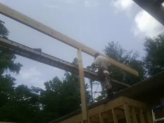 Carpenter setting a ridge beam over a new addition frame — Ice Dam Removal by Roofing Brothers in Hampton Bays