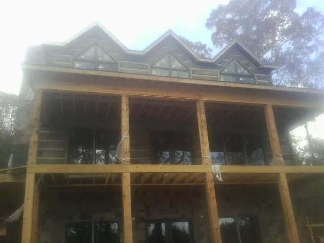 Dormers and porch framing on a large log home under construction — Roof Coating work by our crew in Hampton Bays