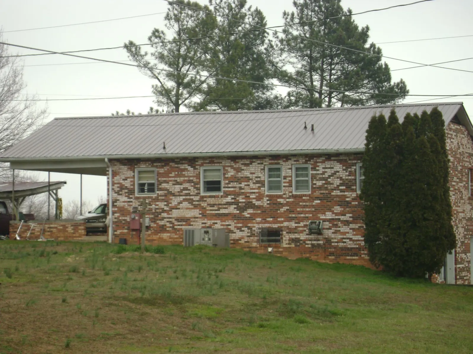Gray metal roof on a brick split level home with a carport in Hampton Bays