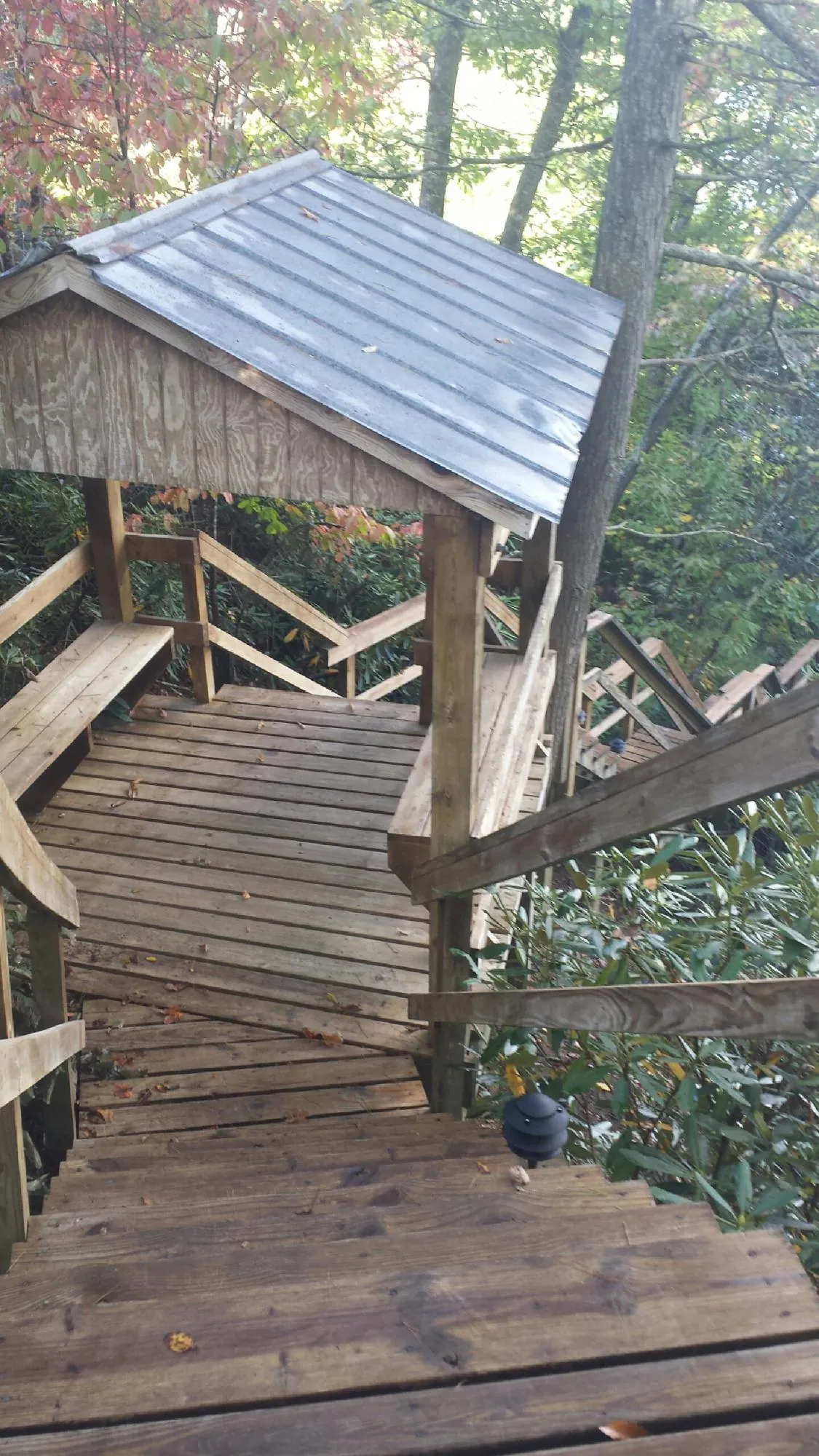 Metal roofed shelter over wooden steps on a wooded walkway — Skylight Repair & Installation work by our crew in Hampton Bays