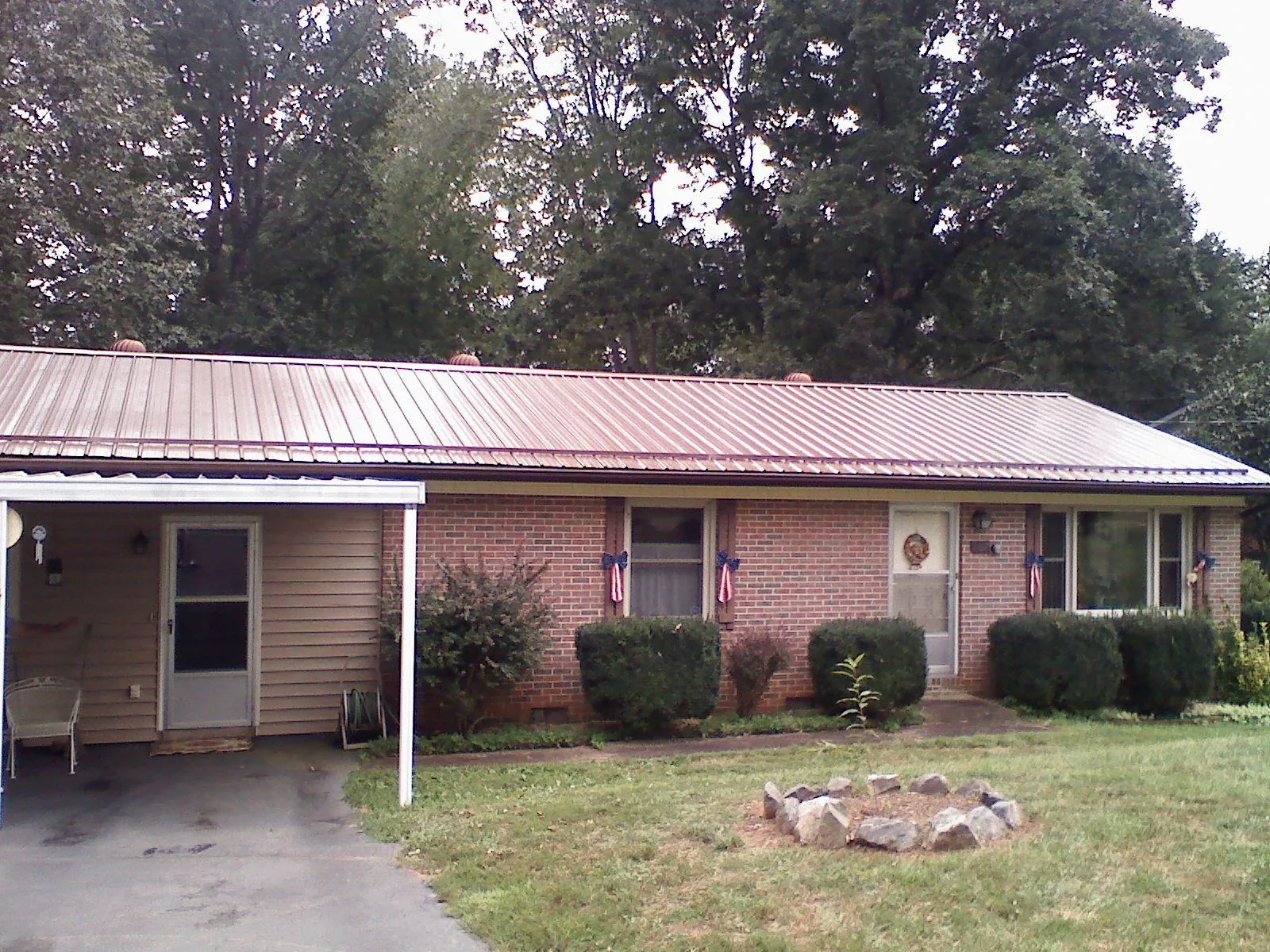 Bronze metal roof and carport on a brick ranch home — Roof Repair work by our crew in Hampton Bays