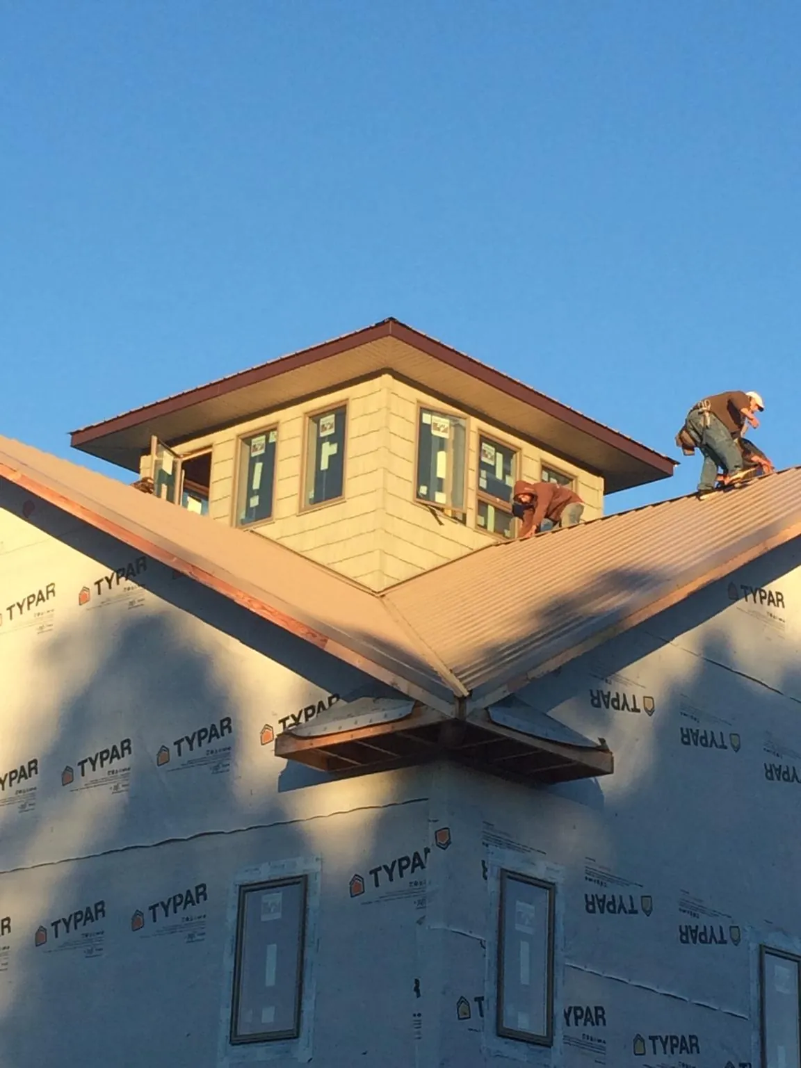 Roofers working around a rooftop cupola on a new metal roof at sunset — Roof Waterproofing in Hampton Bays by Roofing Brothers